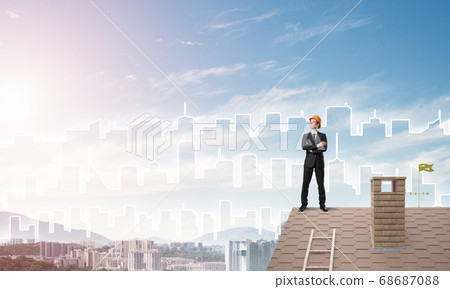 Engineer man standing on roof and looking away. Mixed media 68687088