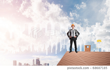 Engineer man standing on roof and looking away. Mixed media 68687185