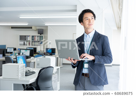 一個年輕的商人，通過清晨獨自一人去辦公室檢查電子郵件 68689075