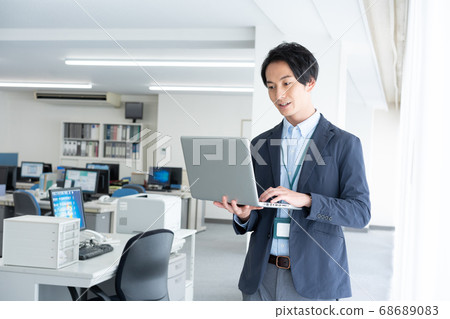 一個年輕的商人,通過清晨獨自一人去辦公室檢查電子郵件 一個年輕的商人,通過清晨獨自一人去辦公室檢查電子郵件 68689083