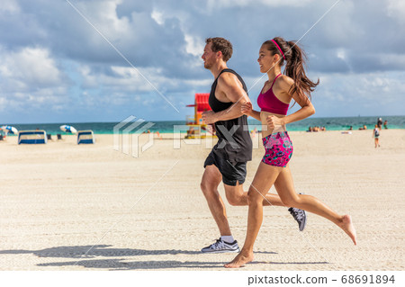 Running people jogging exercising on South Beach, Miami, Florida. Man and woman training partner runners working out together. Lifestyle active people 68691894