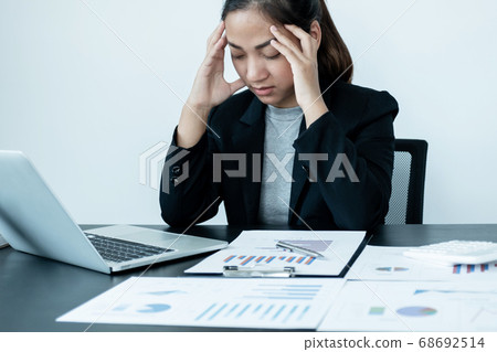 A tired business woman with a stressful headache from work sitting at an office desk 68692514