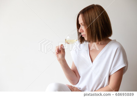 Caucasian brunette girl sommelier holding glass of white wine Caucasian brunette girl sommelier holding glass of white wine 68693889