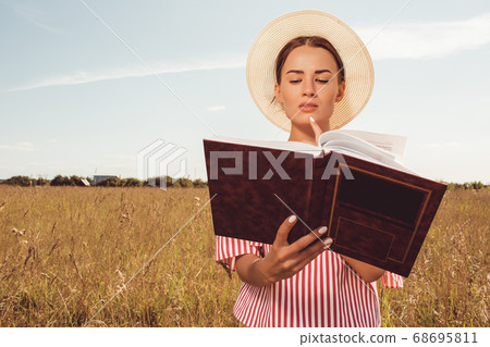 Portrait beautiful girl reading a book in the field Portrait beautiful girl reading a book in the field 68695811