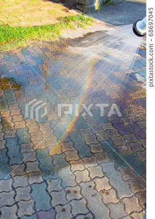 Sprinkle water with a hose to make a rainbow Sprinkle water with a hose to make a rainbow 68697045