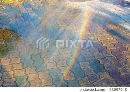 Sprinkle water with a hose to make a rainbow 68697048