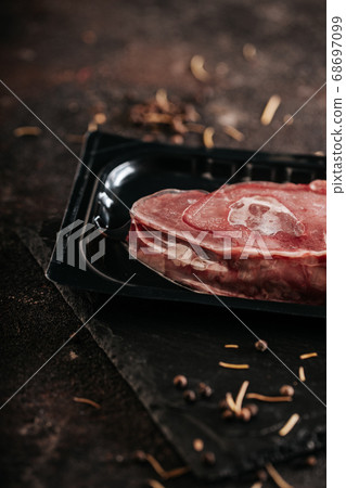 Sirloin steak preparation, seasoning with pepper and salt. Chef preparing fresh meat on dark marble plate 68697099