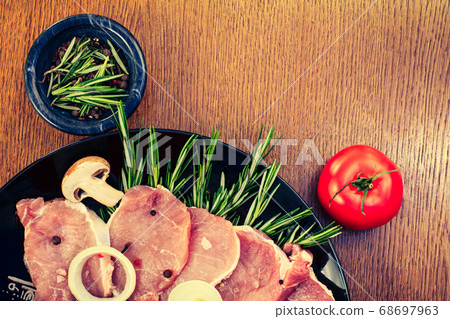 Pieces of raw pork steak and ingredients on a 68697963