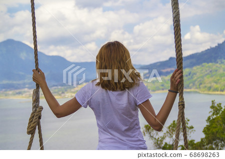 Young girl swinging overlooking a lake and Young girl swinging overlooking a lake and 68698263