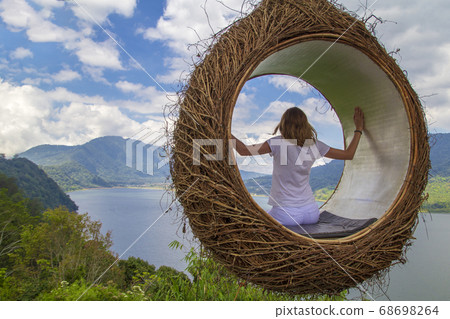 A young girl swinging on a swing in the form of a A young girl swinging on a swing in the form of a 68698264