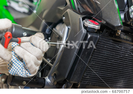 The master performs maintenance on the motorcycle. The master performs maintenance on the motorcycle. 68700757