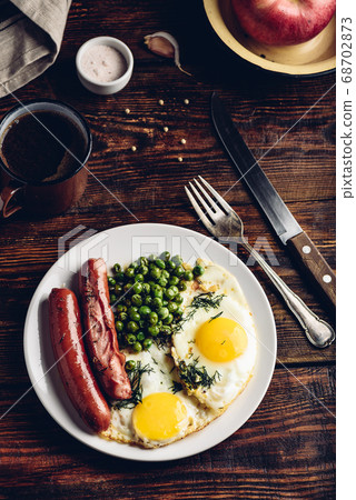 Breakfast with fried eggs, sausages and green peas 68702873