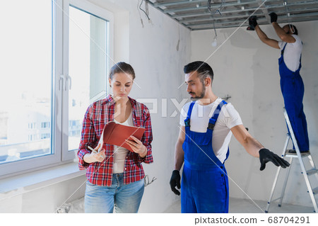 The woman checks the work of the builders in the apartment and writes a note 68704291