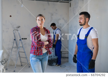 The woman is disappointed with the way the foreman renovates the apartment The woman is disappointed with the way the foreman renovates the apartment 68704292
