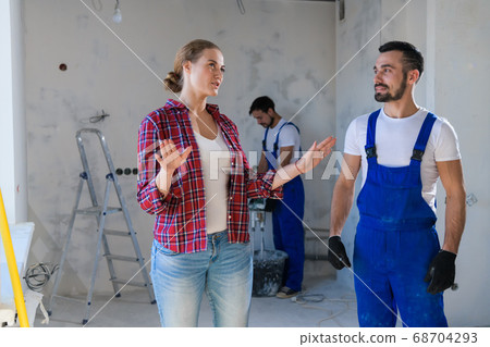 The woman tells the repairman how to make repairs The woman tells the repairman how to make repairs 68704293
