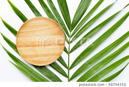 Empty wooden plate on tropical palm leaves  68704358
