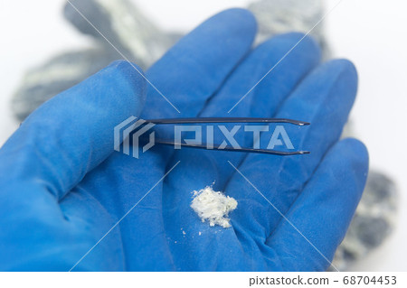 Mineral asbestos lies on the palm in a glove. 68704453