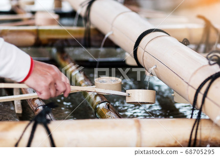 Tourist washing hands in pavilion at Fushimi Inari 68705295
