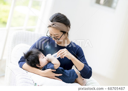 Mother giving milk to a 5 month old baby Mother giving milk to a 5 month old baby 68705487