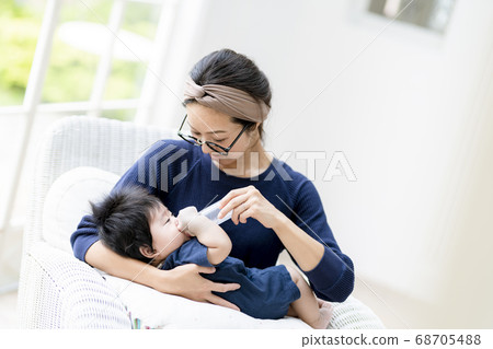 Mother giving milk to a 5 month old baby Mother giving milk to a 5 month old baby 68705488