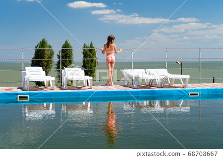 girl in bathing suit between sun loungers by pool 68708667