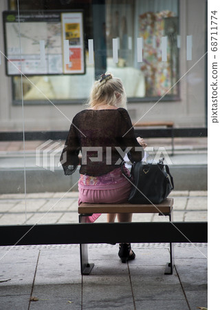 Portrait on back view of woman sitting on the bus stop Portrait on back view of woman sitting on the bus stop 68711774