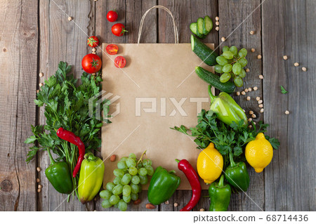 Paper grocery bag with fresh vegetables and fruits on rustic wooden table from above Paper grocery bag with fresh vegetables and fruits on rustic wooden table from above 68714436