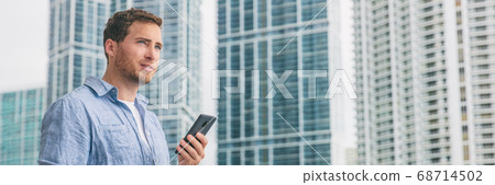 Phone lifestyle young man walking to work on commute businessman using mobile texting sms message outside in city street with condo buildings skycrapers in background Phone lifestyle young man walking to work on commute businessman using mobile texting sms message outside in city street with condo buildings skycrapers in background 68714502