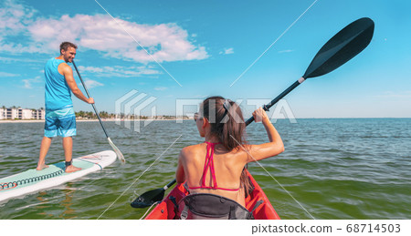 Couple kayaking and paddle boarding fitness man in ocean Paddleboard beach people on stand-up paddle boards surfing in Tourists kayakers woman and man enjoying SUP kayak watersport Keys, Florida, USA 68714503