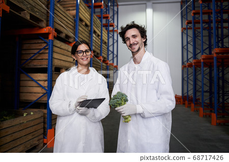 Two pleased warehouse employees smiling at the camera Two pleased warehouse employees smiling at the camera 68717426