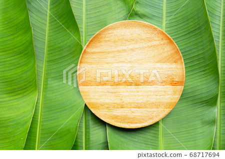 Empty wooden plate on banana leaves background. 68717694