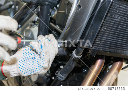 The master performs maintenance on the motorcycle. 68718333