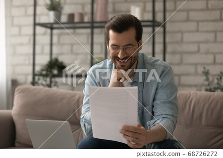 Smiling man feel excited reading good news in paper letter 68726272