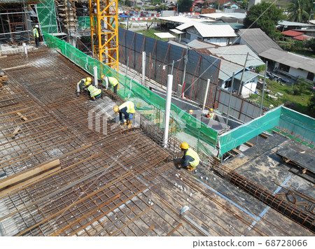 SEREMBAN, MALAYSIA -MARCH 29, 2020: Construction workers fabricating steel reinforcement bar at the construction site. They tied it together using the tiny wires before cover it up using formworks. SEREMBAN, MALAYSIA -MARCH 29, 2020: Construction workers fabricating steel reinforcement bar at the construction site. They tied it together using the tiny wires before cover it up using formworks. 68728066