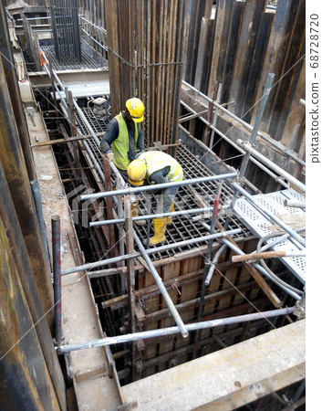 MALACCA, MALAYSIA -MAY 27, 2016: Construction workers fabricating steel reinforcement bar at the construction site in Malacca, Malaysia. The reinforcement bar was ties together using tiny wire. MALACCA, MALAYSIA -MAY 27, 2016: Construction workers fabricating steel reinforcement bar at the construction site in Malacca, Malaysia. The reinforcement bar was ties together using tiny wire. 68728720