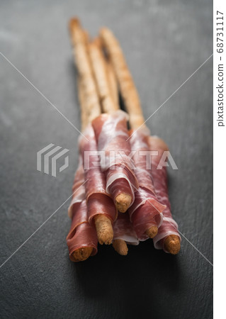 grissini breadsticks with prosciutto on slate background grissini breadsticks with prosciutto on slate background 68731117