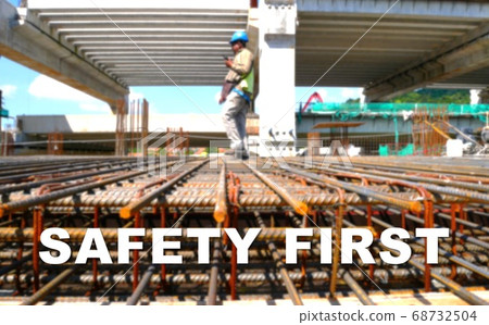 The word SAFETY FIRST is written clearly and against the background of the image of a worker installing a scaffolding. The image has been blurred. 68732504