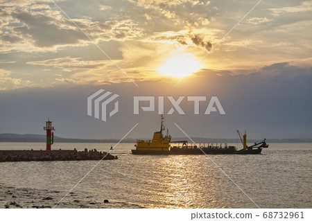 Ship leaving port at sunset. Ship leaving port at sunset. 68732961