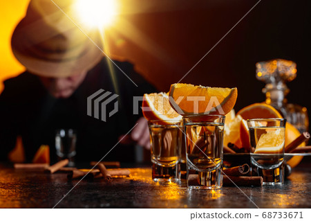 Glasses of tequila with orange and cinnamon sticks Glasses of tequila with orange and cinnamon sticks 68733671