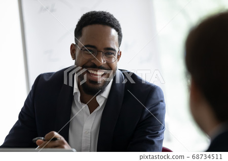 Smiling african businessman communicating with client in office Smiling african businessman communicating with client in office 68734511
