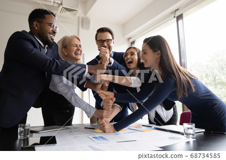 Happy employees coworkers stacking fists together showing corporate spirit Happy employees coworkers stacking fists together showing corporate spirit 68734585
