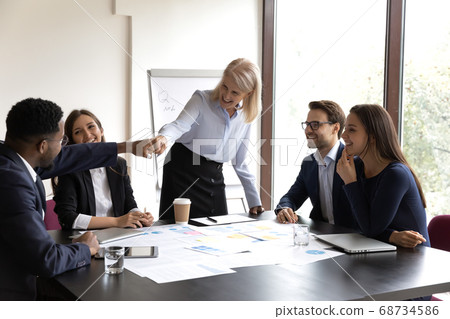 Happy mature businesswoman bumping fists with young african colleague Happy mature businesswoman bumping fists with young african colleague 68734586