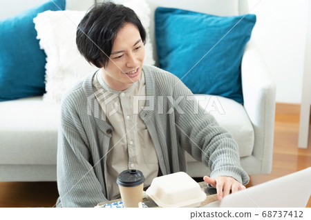 A man enjoying a take-out lunch facing a computer A man enjoying a take-out lunch facing a computer 68737412