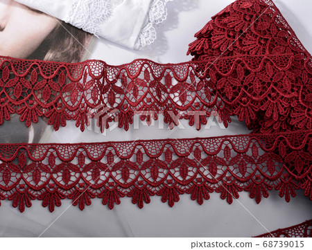 Tapes of red vinous gentle guipure, beauty lace fabric on light background Tapes of red vinous gentle guipure, beauty lace fabric on light background 68739015