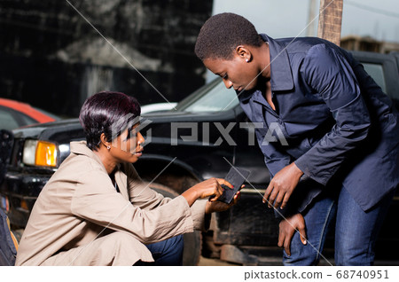 Young woman showing something to her mechanic in Young woman showing something to her mechanic in 68740951