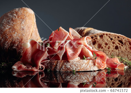Prosciutto with ciabatta and thyme on a black 68741572