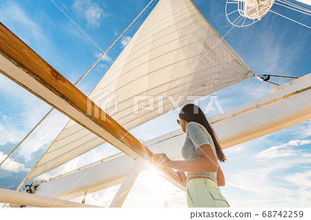 Luxury cruise ship vacation woman on yacht deck at sunset. Travel in Tahiti sail and mast on sky. Boat passenger sailing away on tropical getaway traveling in French Polynesia Luxury cruise ship vacation woman on yacht deck at sunset. Travel in Tahiti sail and mast on sky. Boat passenger sailing away on tropical getaway traveling in French Polynesia 68742259