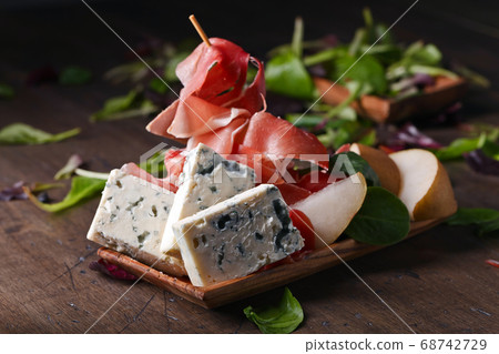 blue cheese with prosciutto and pear on a wooden blue cheese with prosciutto and pear on a wooden 68742729