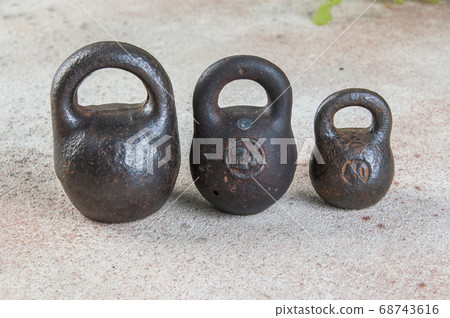 Three antique iron weights for scales on concrete 68743616