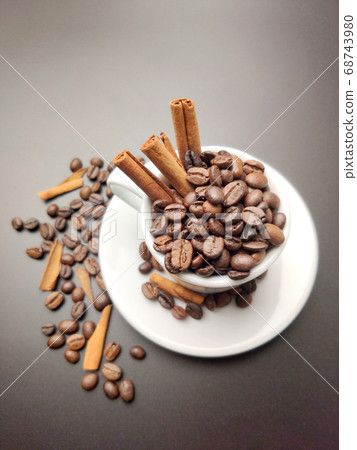 scattered coffee beans, a Cup with coffee beans and cinnamon sticks on a black background scattered coffee beans, a Cup with coffee beans and cinnamon sticks on a black background 68743980